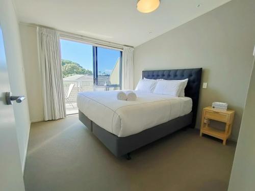 a bedroom with a large bed and a large window at Mount Stunner with King Beds in Mount Maunganui
