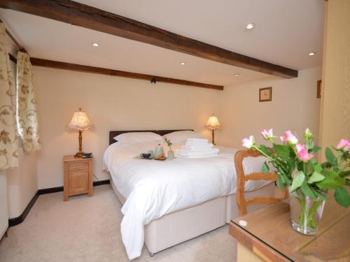 sypialnia z łóżkiem i stołem z kwiatami w obiekcie 2 Bed in Exmoor 83062 w mieście Challacombe
