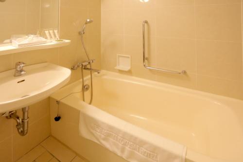 un bagno con un lavandino, una vasca da bagno e un lavandino di Kurashiki Kokusai Hotel a Kurashiki