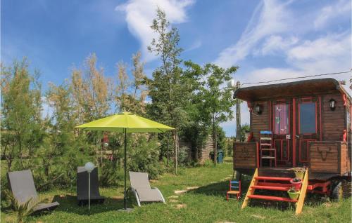 une petite maison avec un parasol jaune et des chaises dans l'établissement Amazing Stacaravan In Franquevaux, à Franquevaux