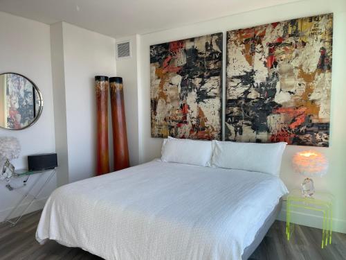 a bedroom with a white bed and a painting on the wall at Massive Penthouse Overlooking All of San Diego in San Diego