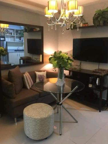 een woonkamer met een bank en een tafel bij Elegant 2BR Hampton Suites with Pool & WIFI in Anabu Primero