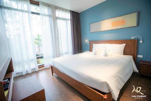 um quarto com uma grande cama branca com paredes azuis em AQ Story Villa Vĩnh Phúc em Phúc Yên