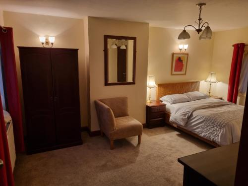 um quarto com uma cama, uma cadeira e um espelho em Maryland Cottage Nr Gatwick em Godstone