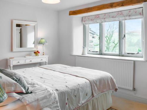 a white bedroom with a bed and a window at Tophams Laithe in Kilnsey