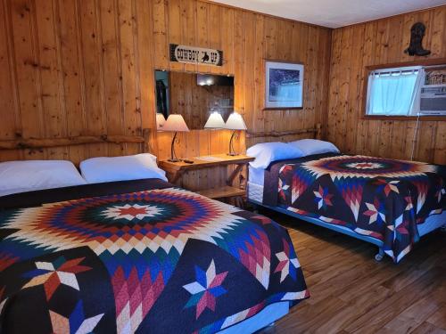 - 2 lits dans une chambre dotée de murs en bois dans l'établissement Outpost Motel on the River, à Dolores