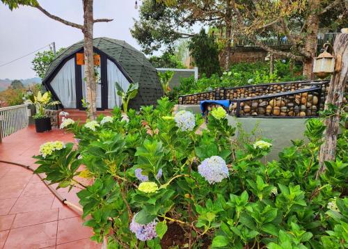 a garden with flowers and a small house at Lê Đinh’s House in Di Linh