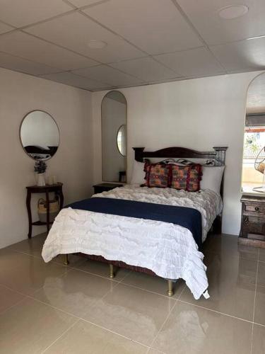 a bedroom with a bed and a mirror in it at Casa Geranios Antigua in Antigua Guatemala