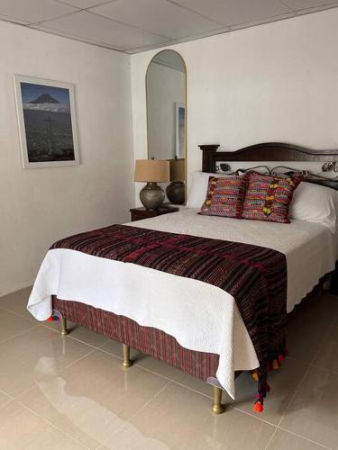 a bedroom with a large bed and a mirror at Casa Geranios Antigua in Antigua Guatemala