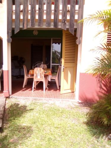 a patio with a table and chairs on a porch at Princess des Iles in Sainte-Anne