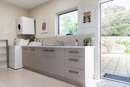 a white kitchen with a sink and a window at Riverview Escape in Inveresk