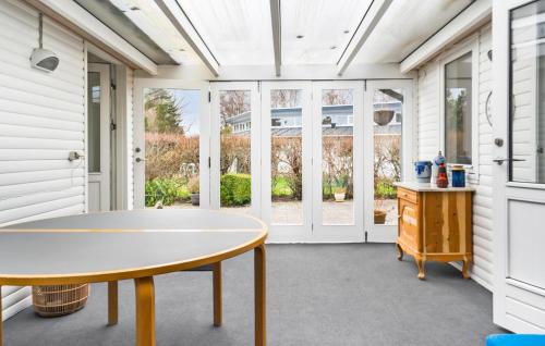 a screened in porch with a table and windows at 3 Bedroom Beautiful Home In Juelsminde in Juelsminde