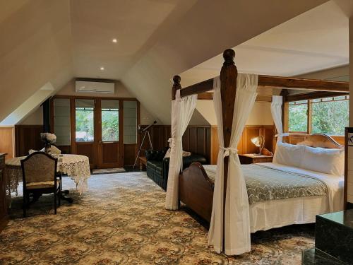 Arnica Views Summit Retreat في ماونت داندينونج: غرفة نوم مع سرير المظلة ومكتب