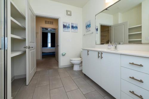 a bathroom with a toilet and a sink and a mirror at Stunning Nulu 1BR CozySuites 06 in Louisville
