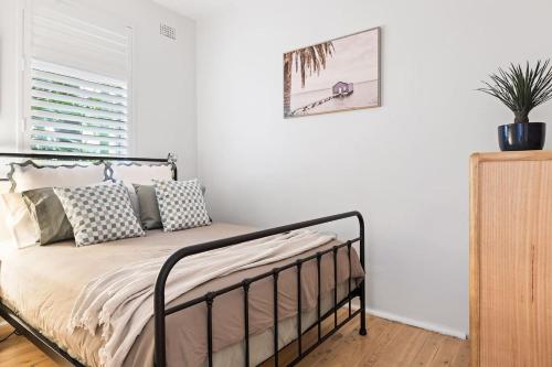 ein Schlafzimmer mit einem Bett mit Kissen darauf in der Unterkunft Coastal Corner - Contemporary Chic by the Beach in Sydney