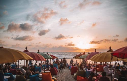 una multitud de personas sentadas en una playa con sombrillas en Bahana Guest House, en Kuta