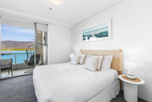 une chambre blanche avec un lit et un balcon dans l'établissement Lux Waterfront - prime location Pool Gym & Sauna, à Cairns
