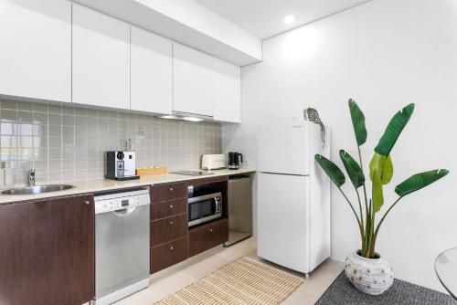 a kitchen with white cabinets and a white refrigerator at Lux Waterfront at Habour Lights I prime location Pool, Gym & Sauna in Cairns