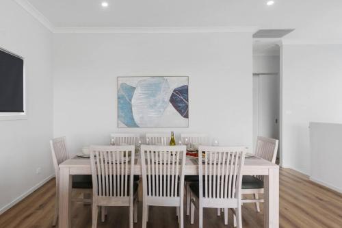 a dining room with a white table and chairs at South Beach Escape - Sensational Shell Cove Living in Shellharbour