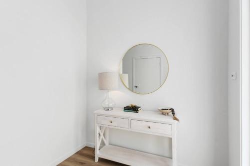 a white dressing table with a mirror on a wall at South Beach Escape - Sensational Shell Cove Living in Shellharbour