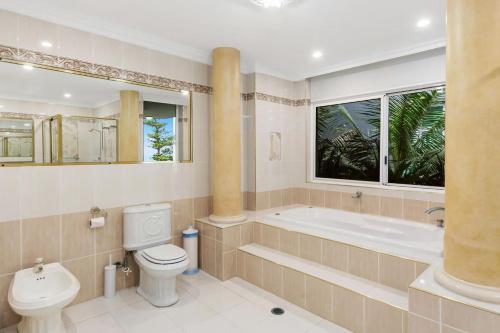 a bathroom with a tub and a toilet and a sink at Ocean Vista Escape - A Lofty Beachfront Penthouse in Wollongong