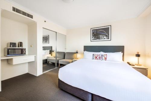 a bedroom with a large bed and a living room at Oaks Sydney Castlereagh Suites in Sydney