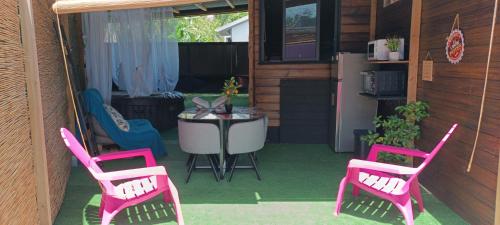 a patio with pink chairs and a table and a refrigerator at ô Bois Dormant, Bungalow & jacuzzi privé in Saint-André