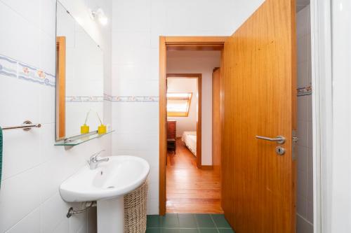 a bathroom with a sink and a wooden door at Casa Amarela, 9-room beach house in Praia da Barra