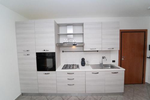 a kitchen with white cabinets and a sink and a microwave at Stile e comfort! in Trecate
