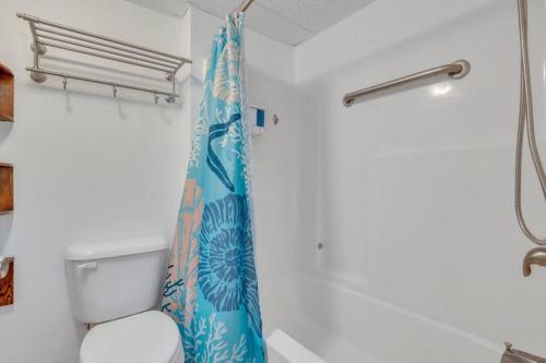 a bathroom with a toilet and a shower curtain at The Sea & Breeze:1 Bed Condo w/Pool Steps to Beach in Tybee Island
