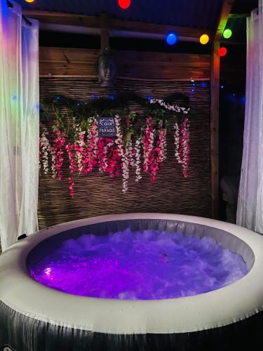 a jacuzzi tub with purple water and lights at ô Bois Dormant, Bungalow & jacuzzi privé in Saint-André