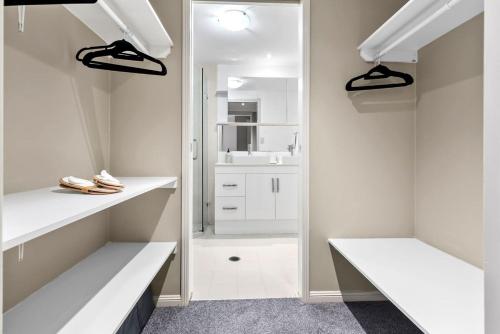 a white bathroom with white counters and a mirror at Reef Apartment Cairns in Edge Hill