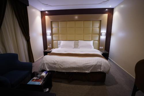 a bedroom with a large bed and a blue couch at Ertiaad Tabuk for Hotel Apartment in Tabuk