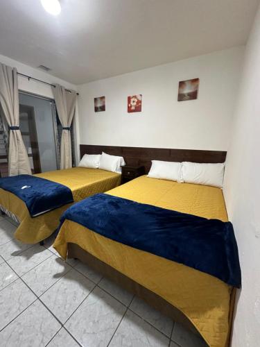 two beds in a room with yellow and blue sheets at Casa Alicia Hostal Antigua Guatemala in Antigua Guatemala