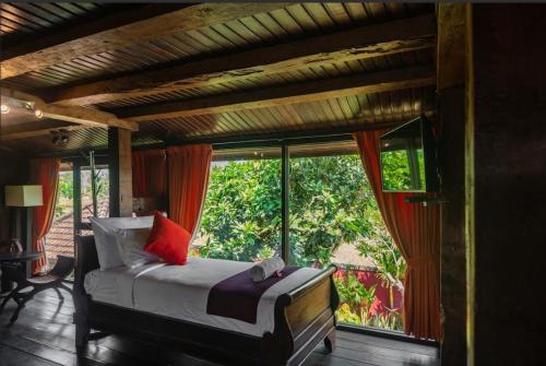 Balam Bali Villa في Mengwi: غرفة نوم بسرير ونافذة كبيرة