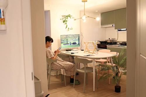 una mujer sentada en una mesa frente a una computadora en 3rooms 4beds kitchen Hongik Stn 3min en Seúl