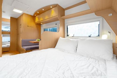 ein großes weißes Bett in einem Zimmer mit Fenster in der Unterkunft Poseidon Caravan in Gapyeong