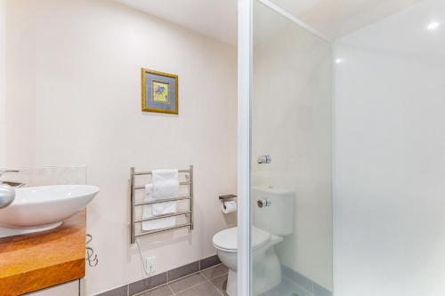 a bathroom with a white toilet and a sink at Zodiak Stays Cozy CBD 2BR Near Top Dining Spots in Auckland