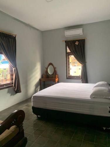 1 dormitorio con 1 cama grande y 2 ventanas en Homestay Mutiara en Yogyakarta