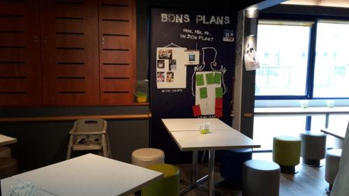a restaurant with tables and stools in a room at Ibis Budget St Gratien - Enghien-Les-Bains in Saint-Gratien