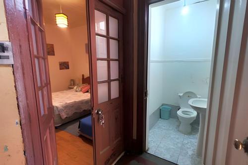 a bathroom with a toilet and a sink and a bed at Casa Argot in Santiago