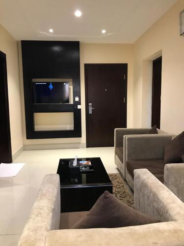 a living room with couches and a table and a tv at Ertiaad Tabuk for Hotel Apartment in Tabuk