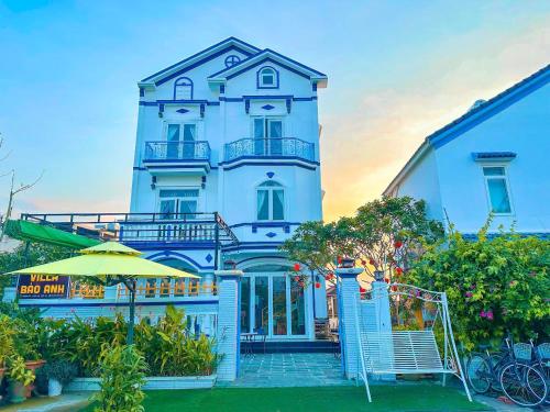 - un grand bâtiment blanc avec un parasol devant dans l'établissement Blue Fish Villa, à Tân Thành (1)