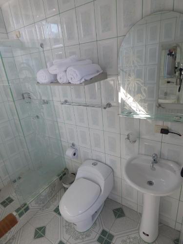 a white bathroom with a toilet and a sink at Stefany's Lodging in Puerto Baquerizo Moreno
