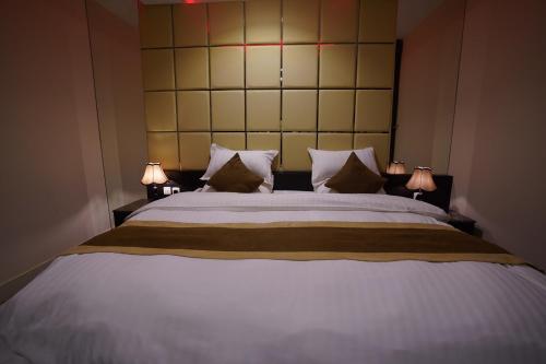 a bedroom with a large bed with two lamps at Ertiaad Tabuk for Hotel Apartment in Tabuk
