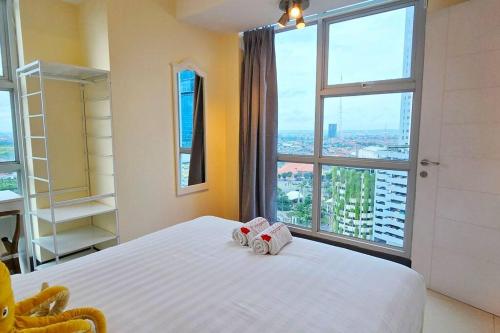 Un dormitorio con una cama blanca con una ventana grande. en StöckHölmm at Anderson apartment, en Surabaya