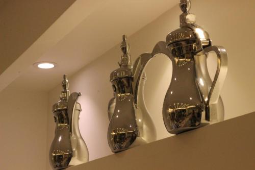 three glass vases on a shelf in a room at Ertiaad Tabuk for Hotel Apartment in Tabuk