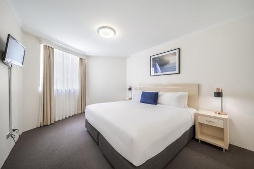 a hotel room with a large bed and a tv at Oaks Sydney Castlereagh Suites in Sydney
