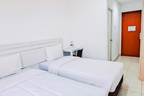 dwa białe łóżka w pokoju z czerwonymi drzwiami w obiekcie Gading Serpong Hotel Near Stadion Persita Redpartner w mieście Anggris
