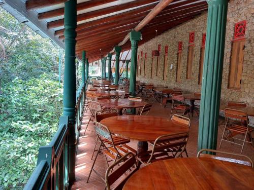 a patio with wooden tables and chairs in a building at Belihuloya Terico Resort in Balangoda